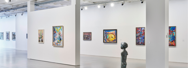 Blick in eine helle Ausstellungshalle mit farbintensiven Gemälden und einer Bronzeplastik.