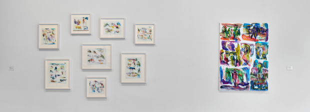 Ausstellungsansicht mit mehreren farbigen kleinformatigen Zeichnungen links und farbiger Großzeichnung rechts.