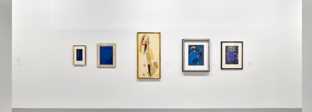 Wandansicht mit abstrakten Gemälden in Blau und Beige.