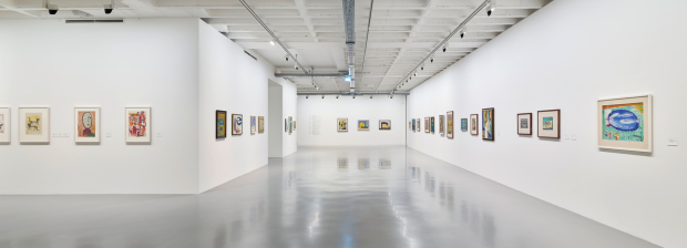 Großer Raum mit Gemälden und Grafiken an weißen Wänden.