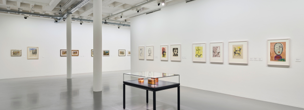 Ausstellungsansicht mit Zeichnungen und Vitrine im Vordergrund.