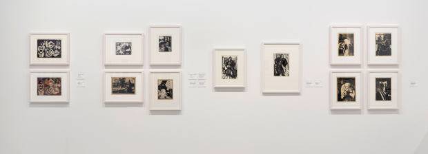 Wandansicht mit Schwarz-Weiß-Druckgrafiken in Gruppen gehängt.