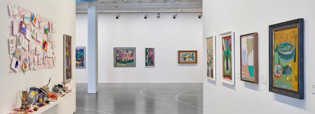 13.	Blick zwischen zwei Ausstellungswänden mit Gemälden und einer offenen Installation links. 