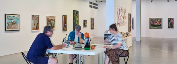 Drei Personen arbeiten an einem Tisch inmitten der Ausstellung im Kunstmuseum Singen. 