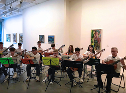 Gitarrenensemble junger Musiker:innen bei einem Konzert im Kunstmuseum vor Gemälden aus der Sammlung.