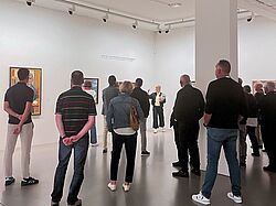 Besucher im Kunstmuseum lauschen einer Führung und blicken auf Bilder