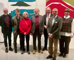 Sieben Menschen - Frauen und Männer - posieren vor der Kamera ; im Hintergrund: farbenfrohe Werke des Künstler Markus Weggenmann