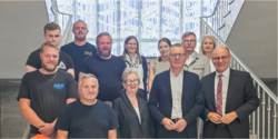 Gruppenfoto im Treppenhaus vor gläserner Wandinstallation im Rathaus Singen.