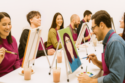 Paare sitzen sich im Atelier gegenüber und malen Portraits