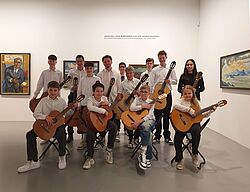 Jugendliches Gitarrenensemble posiert im Ausstellungsraum des Kunstmuseums Singen mit Gemälden im Hintergrund.